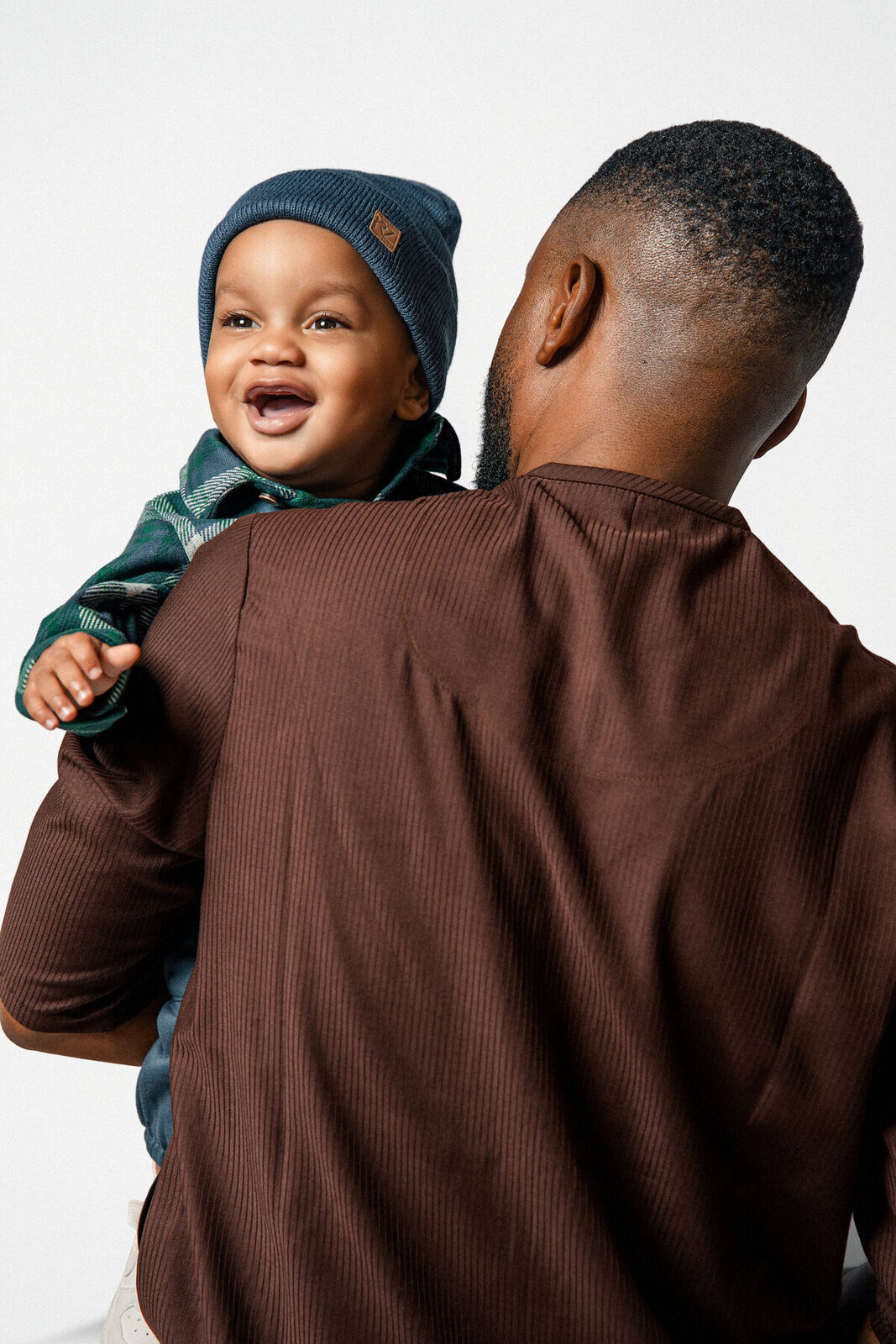 A toddler laughing over his father's shoulder