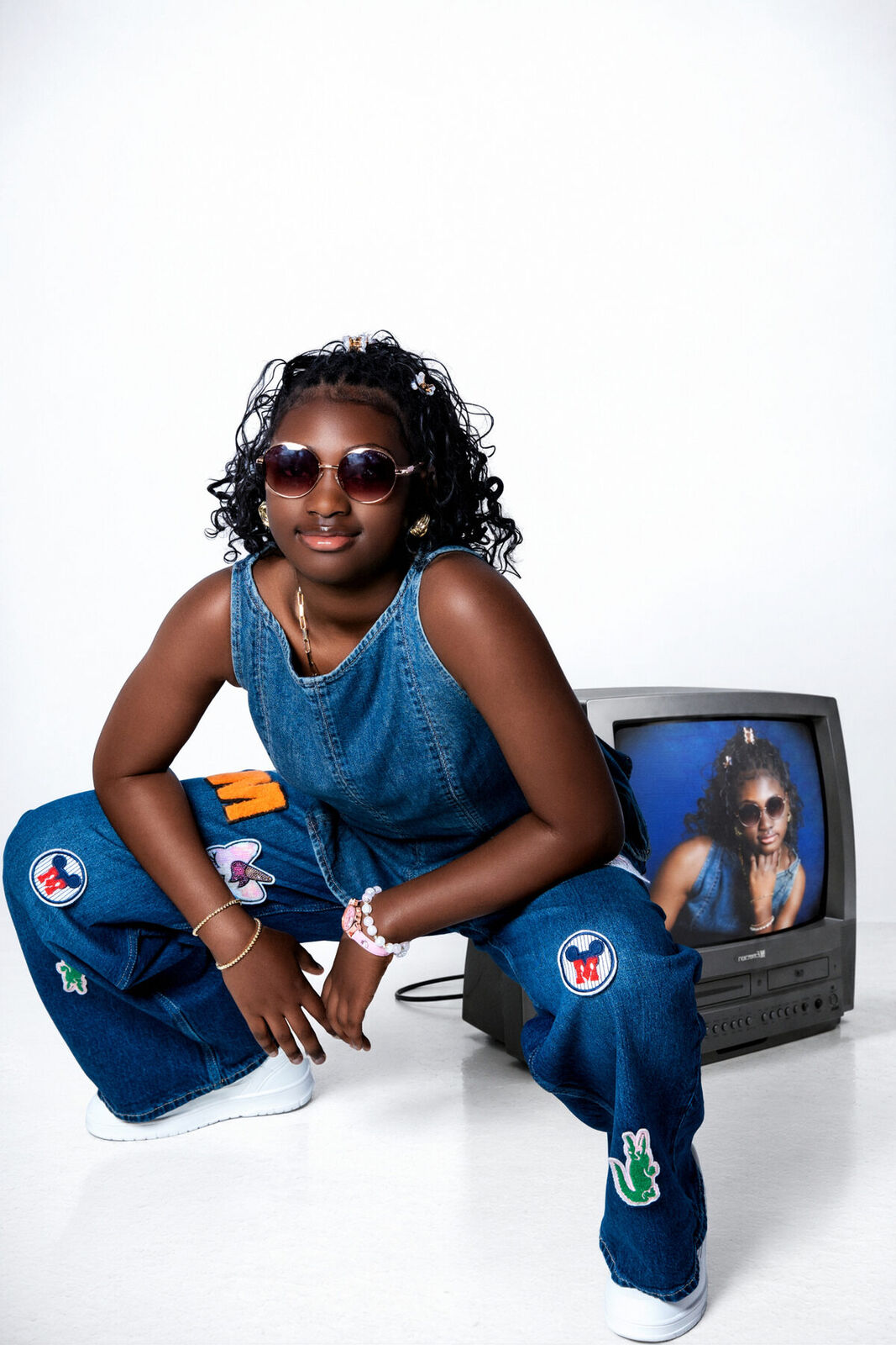 Studio portrait in denim beside a vintage television