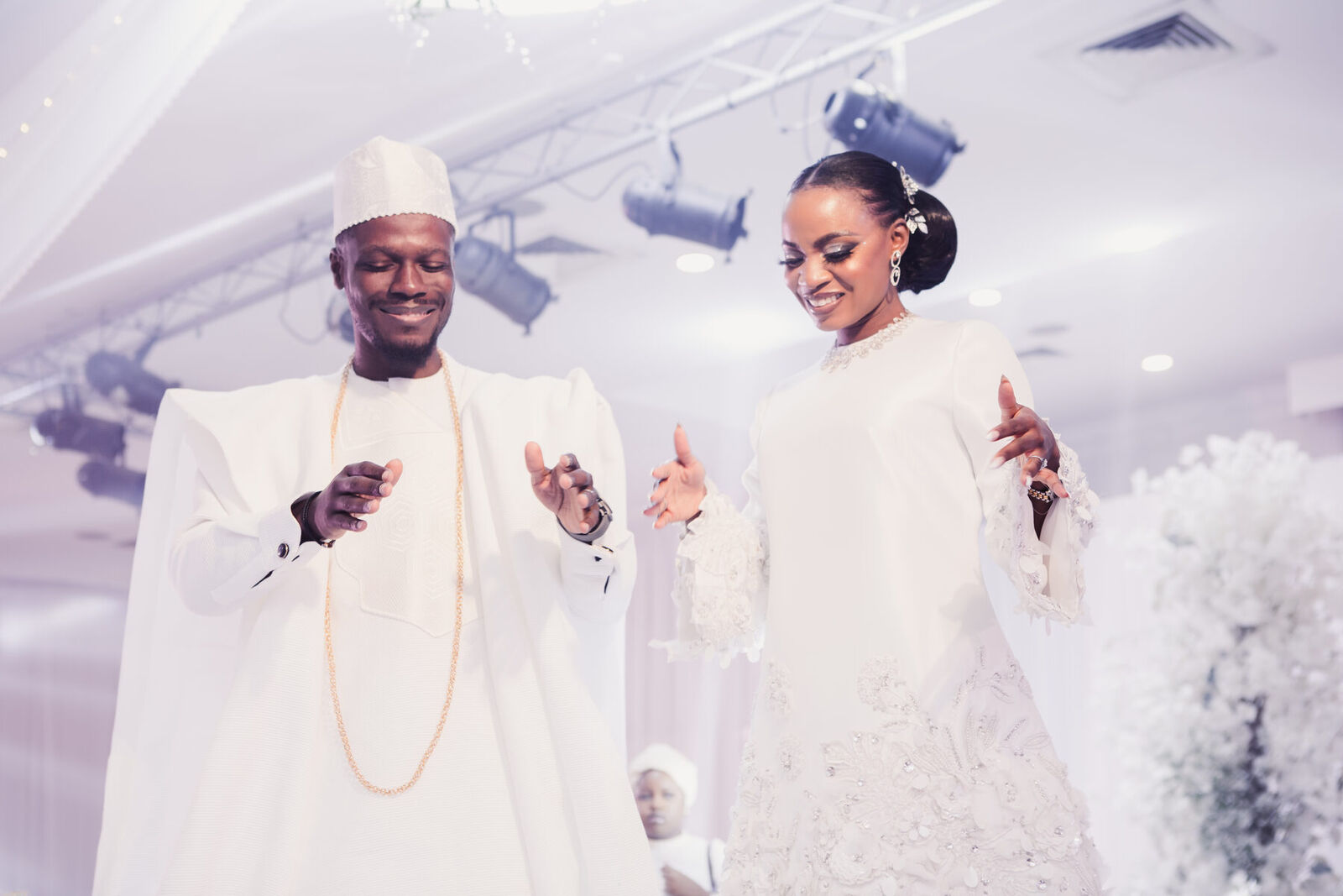 The couple in white, dancing beneath a canopy of flowers at their wedding